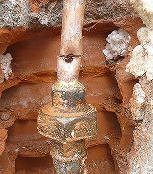 Un tuyau d'alimentation d'eau froide encastré dans le mur percé net